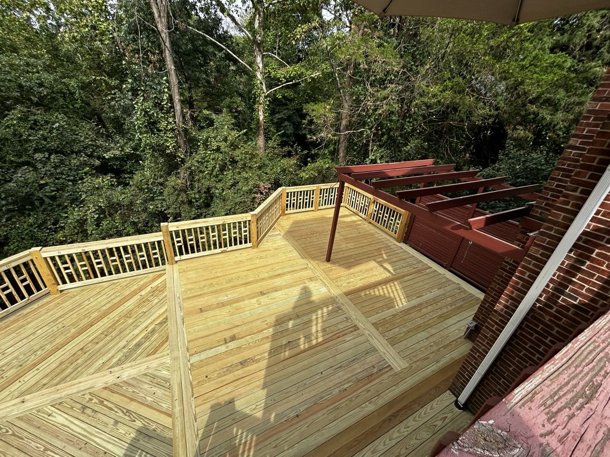 Angled view of patterned wood decking with border boards, decorative railings and a brick wall