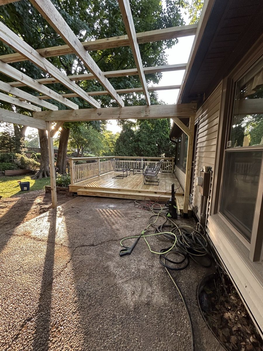 Timber pergola framing over a patio beside a deck during construction