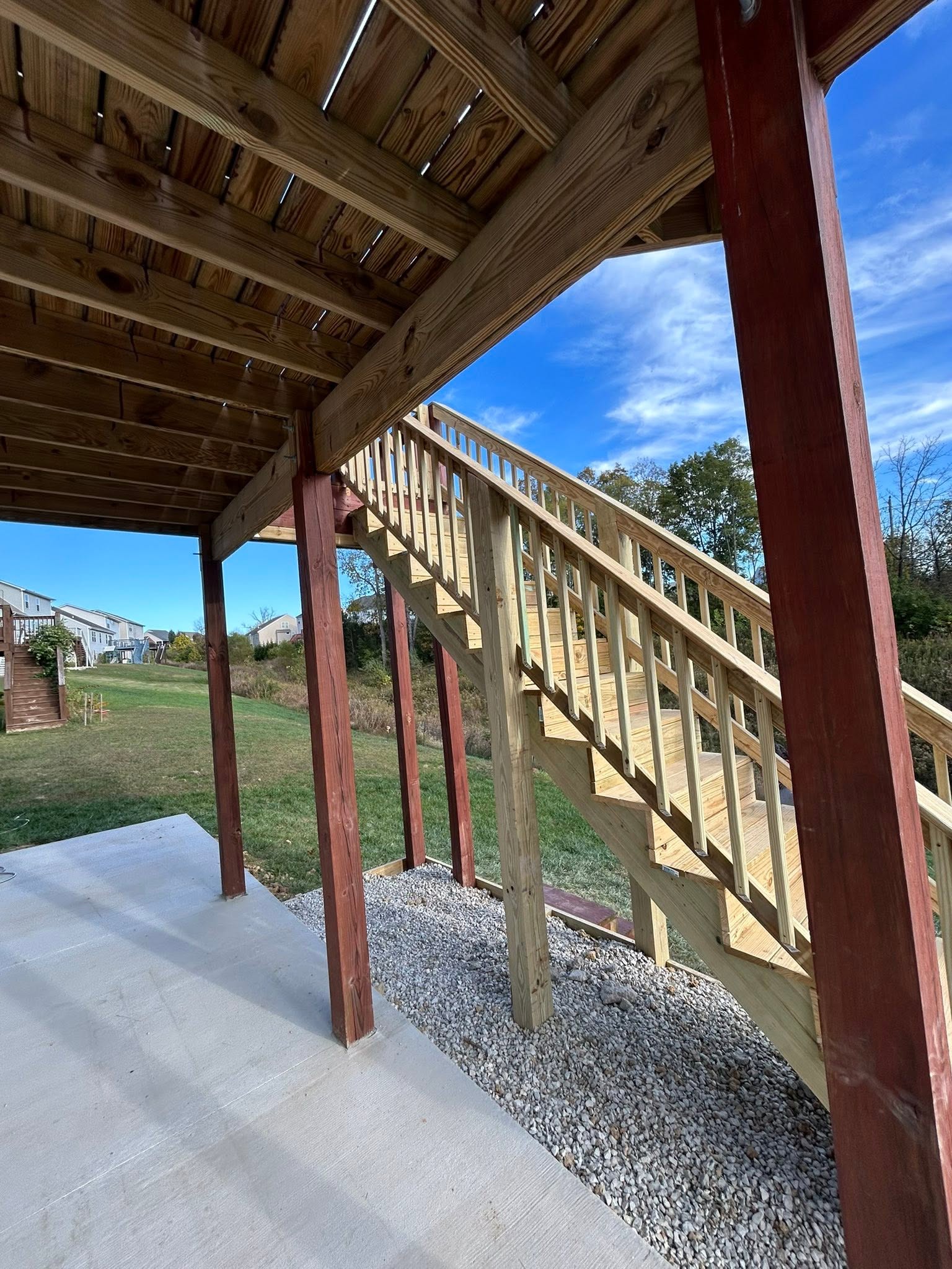 Side view of timber stairs and railings beneath an elevated deck, showing the framing above