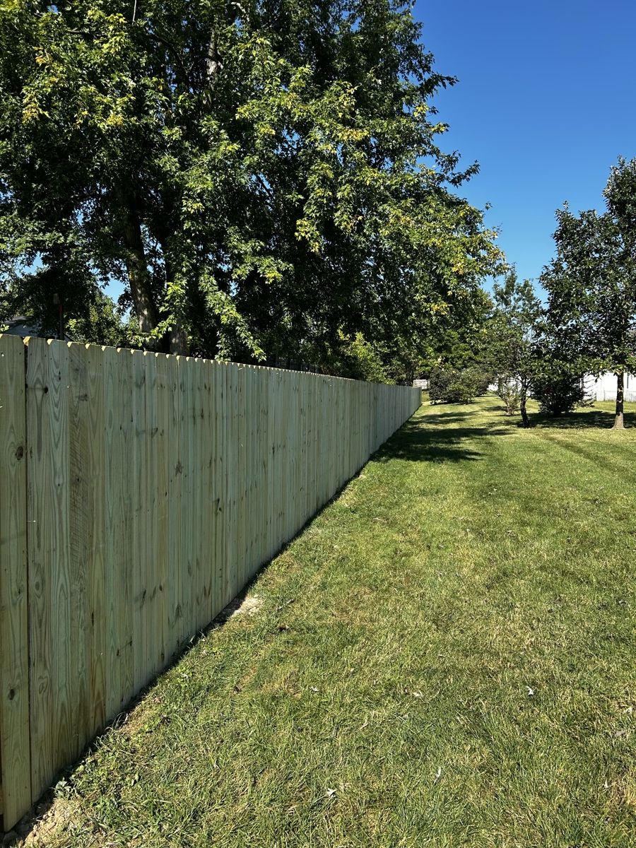 Vertical-board timber privacy fence along a grassy backyard boundary